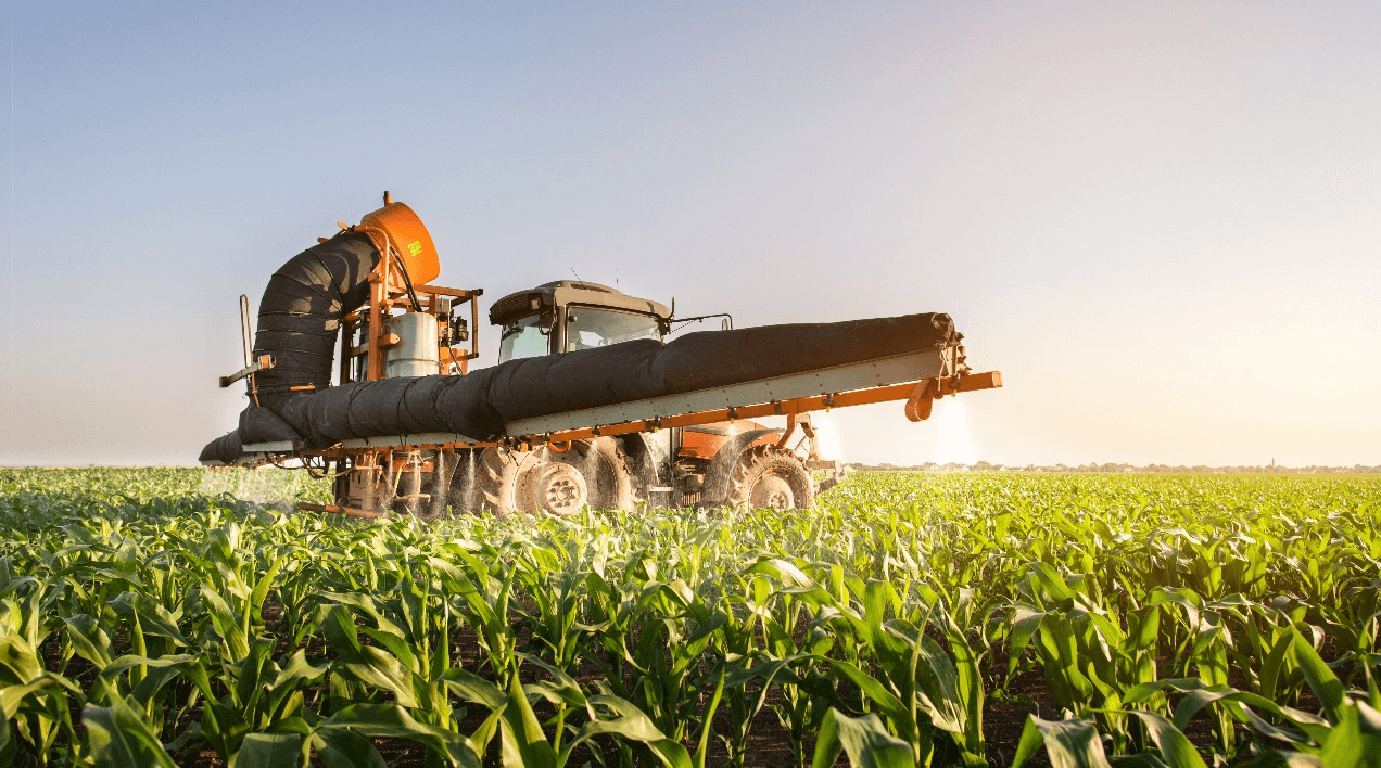 Tractor spraying crops in a sunny field, showcasing modern agriculture technology and sustainable farming practices.